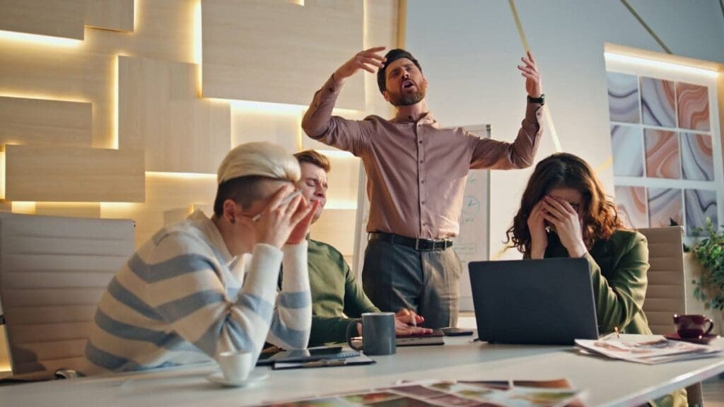 four frustrated people in group at work looking at a computer