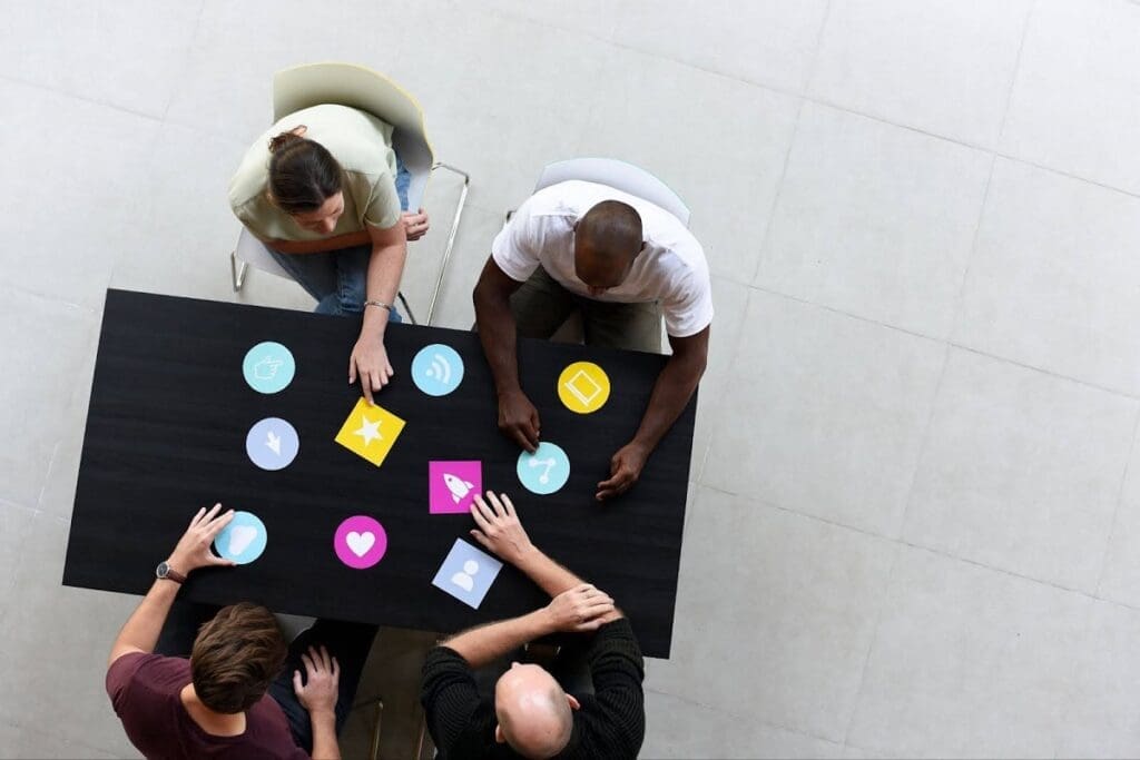 overhead view of four people at a table using social media icons like cards